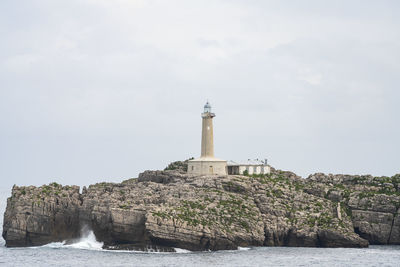 Lighthouse by sea against sky