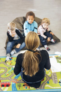 High angle view of teacher sitting in front of children at kindergarten