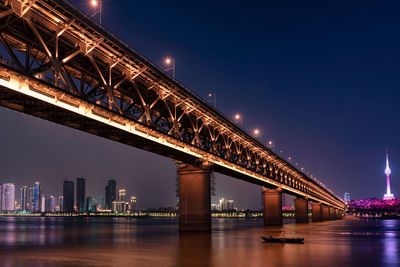 Illuminated bridge over river at night