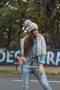 Full length of young woman standing on road against trees