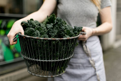 Midsection of woman holding vegetable in basket