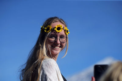 Portrait of smiling woman against blue sky