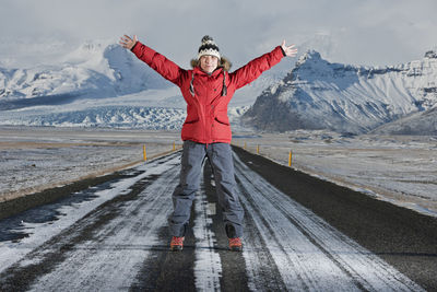 Woman standing in the middle of a highway with her arms stretched out