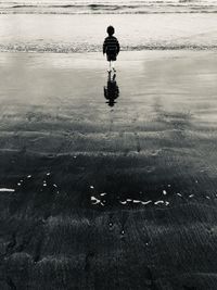 Rear view of boy walking on beach