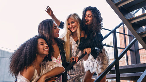 Low angle view of cheerful female friends standing on staircase