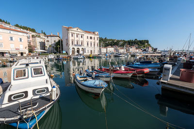 Sailboats moored at harbor against buildings in city