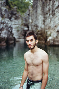 Portrait of shirtless man standing in lake