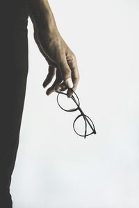 Midsection of woman holding eyeglasses against white background