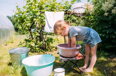 Little preschool girl helps with laundry. child washes clothes in garden