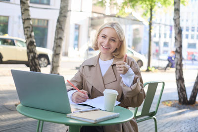 Young woman using laptop at cafe