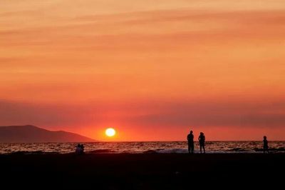Silhouette people on beach at sunset