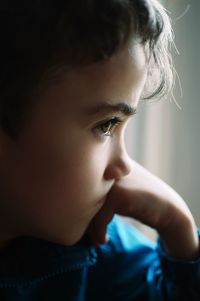 Close-up of thoughtful boy with hand on chin looking away
