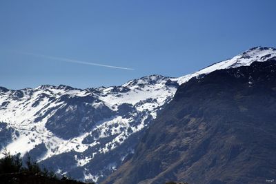 Scenic view of snow covered mountains against blue sky