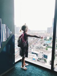 Girl looking through window in city