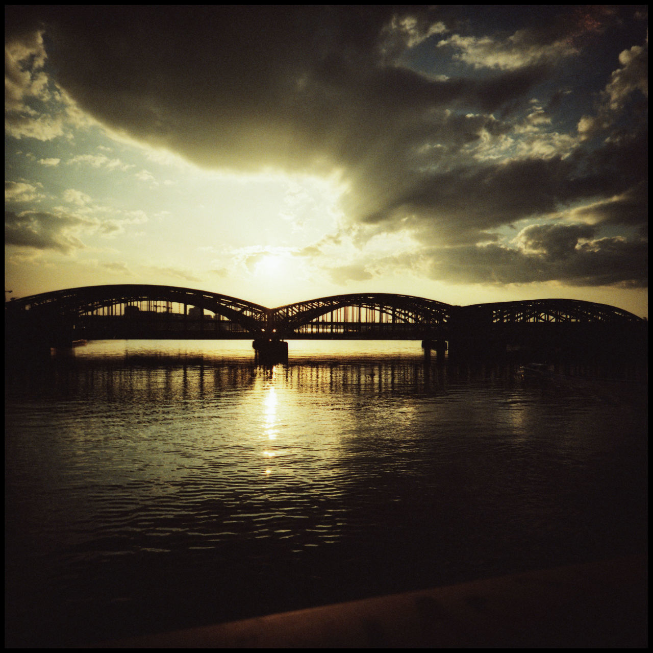 BRIDGE OVER RIVER AGAINST SKY DURING SUNSET