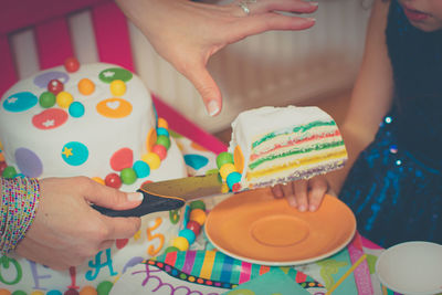 Midsection of woman holding multi colored cake