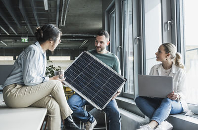 Multiracial business colleagues discussing over solar panel in meeting at office