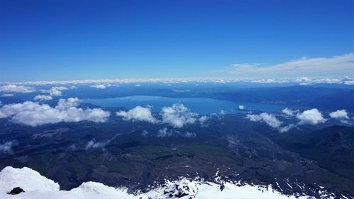 Aerial view of landscape and sea against blue sky