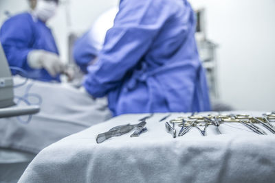 Midsection of surgeons operating patient by surgical equipment in hospital