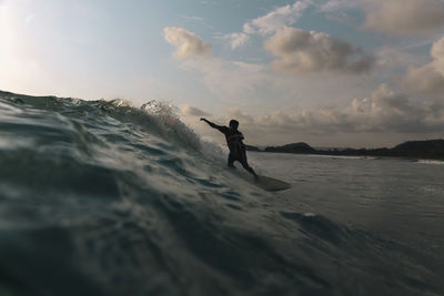 Surfer on a wave at sunset time