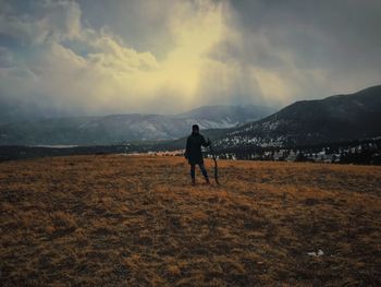 Woman standing on field against sky during winter