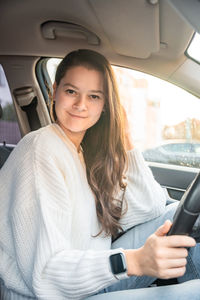 Young woman using mobile phone while sitting in car