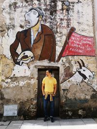 Full length of man standing against graffiti wall