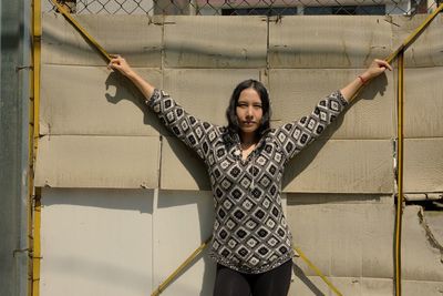 Portrait of young woman standing against wall