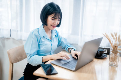 Businesswoman using laptop while sitting on table