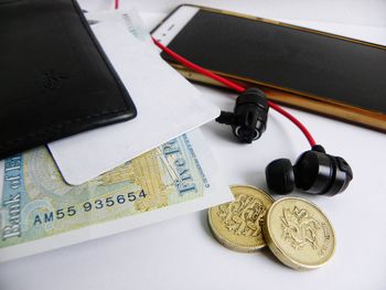 High angle view of smart phone and currency on table