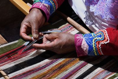 Midsection of person weaving textile in factory