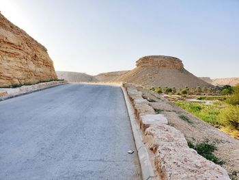 Road leading towards mountains against clear sky