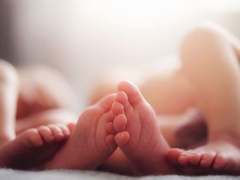 Cropped image of baby on bed