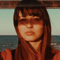 Close-up portrait of young woman against sea