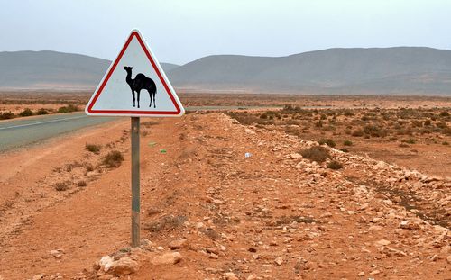 Road sign on landscape against sky