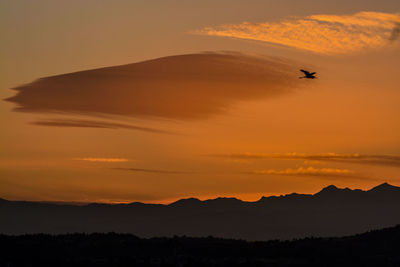 Scenic view of silhouette mountains against orange sky