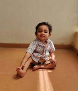 Portrait of cute boy sitting on floor at home