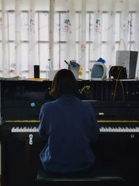 Rear view of woman playing piano