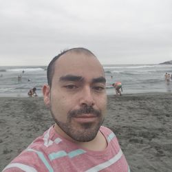 Portrait of mature man on beach against sky