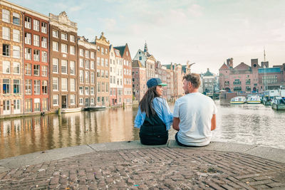 Rear view of couple sitting at riverbank