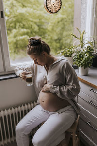 Pregnant woman drinking coffee in kitchen