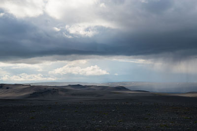 View of desert against cloudy sky