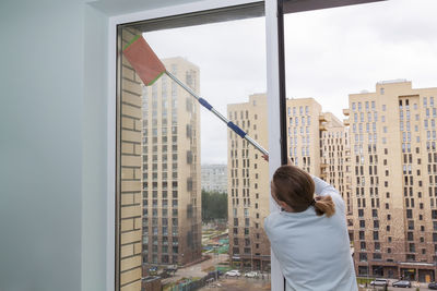 Rear view of woman standing by buildings against sky