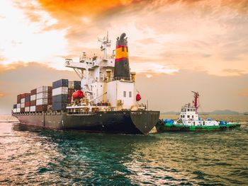 Ship sailing on sea against sky during sunset