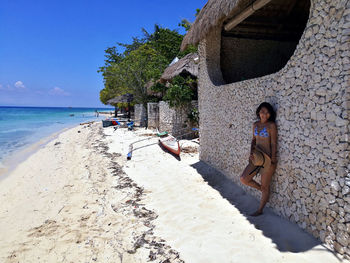 Woman in bikini standing against wall