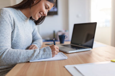 Midsection of woman using mobile phone at home