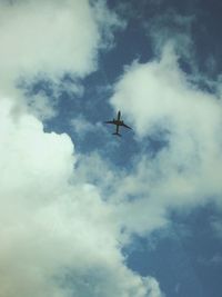 Low angle view of bird flying against cloudy sky