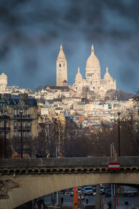 View of buildings in city against cloudy sky