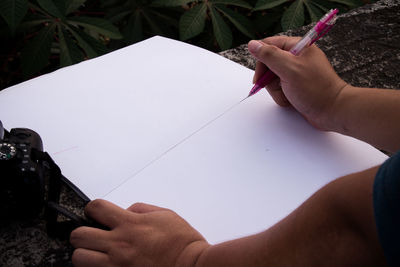 Cropped image of person holding book against paper