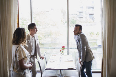 Business people standing by table against window at restaurant